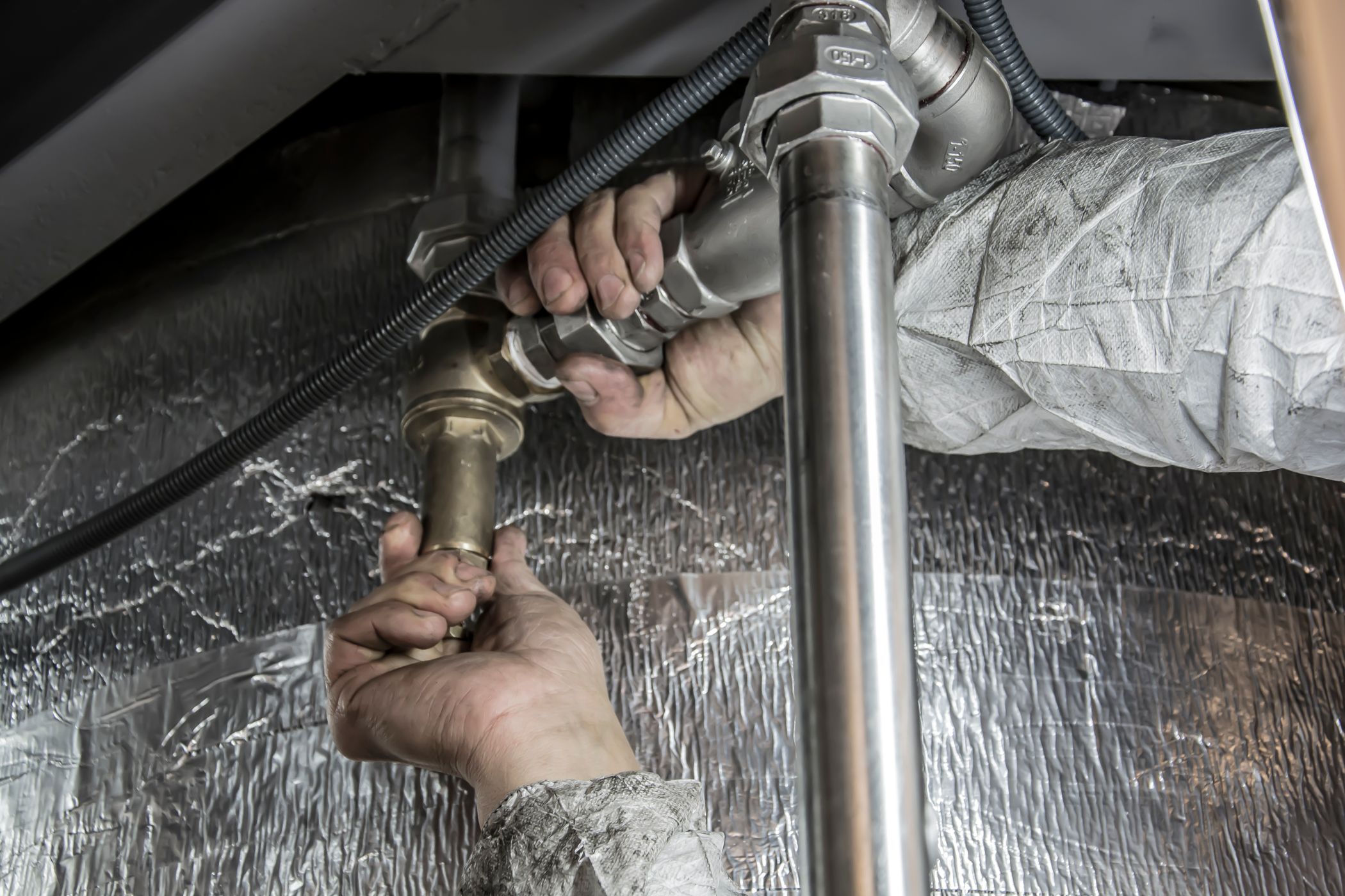 Plumber's hands installing well system piping
